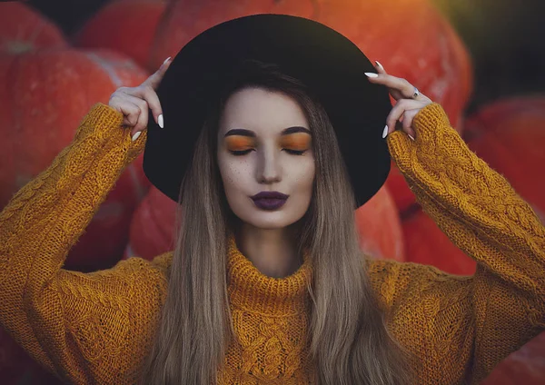 Dromerige meisje in de gele trui en zwarte hoed met ogen dicht op de achtergrond van. Gezellige herfst foto. — Stockfoto