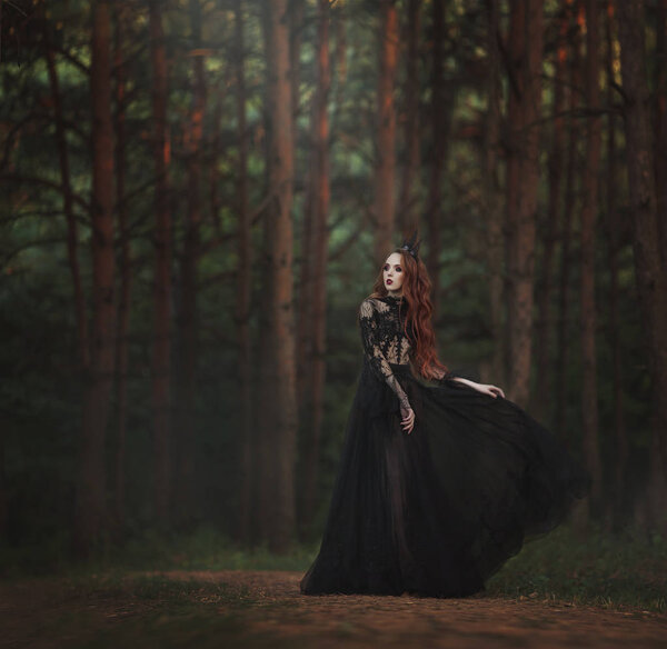A beautiful gothic princess with pale skin and very long red hair in a black crown and a black long dress walks in a misty fairy-tale autumn forest. The costume of the dark queen. Artistic processing.