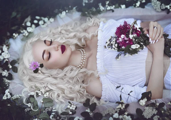 Doornroosje. Betoverde prinses ligt in een kist in met een boeket bloemen. Slapen in de donkere bossen. — Stockfoto