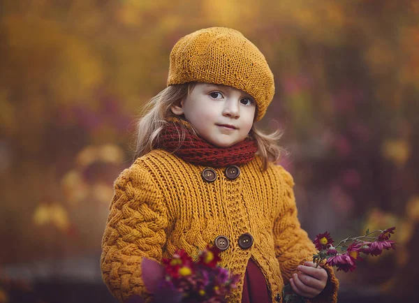 Wunderschönes Herbstporträt eines Kindes mit einem Blumenstrauß. ein kleines Mädchen in Herbstkleidung spaziert durch den Park. — Stockfoto