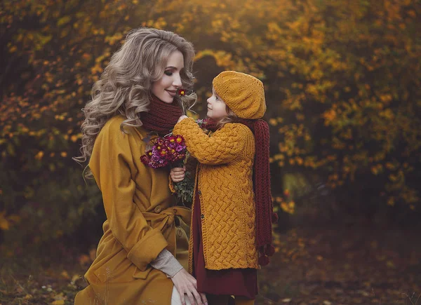 Beautiful autumn portrait happy mother and daughter . My daughter and mother have a good time together and enjoy the autumn. A girl gives a sniff of a flower to her mother. — Stock Photo, Image