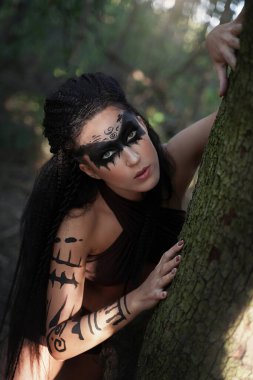 Portret sisli bir ormanda güzel bir kabile şamanının yakın çekimi. Etnik dansçının elleri. Ağacın yanındaki mazon kız. Yumuşak odak