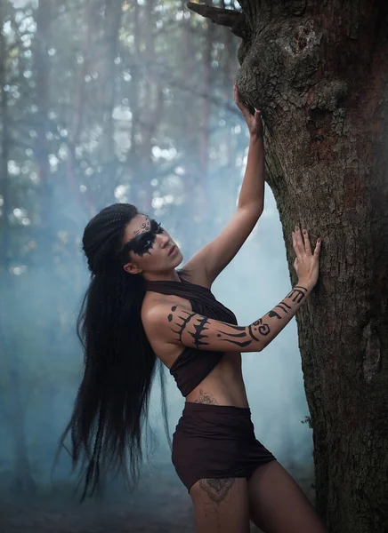 Portret close-up de bela mulher xamã tribal com longos cabelos pretos em uma floresta nebulosa. Mãos de dancer.Amazon étnico menina perto da árvore. Foco suave — Fotografia de Stock