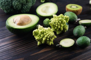  çeşitli yeşil sebzeler, avokado, feijoa, brokoli ve Brüksel lahanası ahşap masa üzerinde. Sağlıklı gıda kavramı, seçici odak