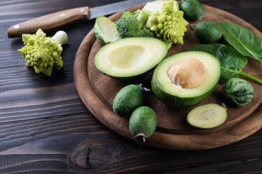  çeşitli yeşil sebzeler, avokado, feijoa, brokoli ve Brüksel lahanası ahşap masa üzerinde. Sağlıklı gıda kavramı, seçici odak