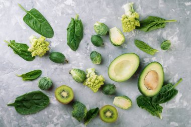 Yeşil sebze ve ıspanak yaprakları gri taş zemin üzerine. Düz la