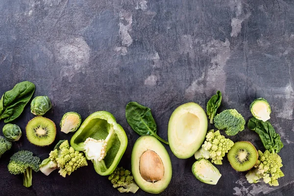 Green vegetables on dark background, broccoli, cabbage, avocado,  pepper,  flat lay