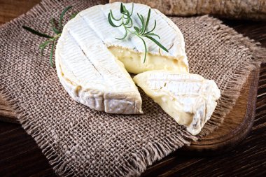 Camembert cheese in burlap  on wooden rustic background clipart