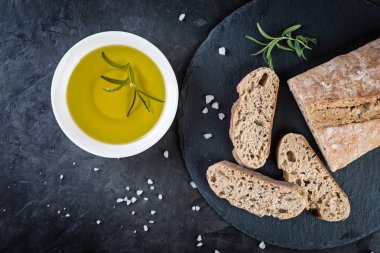 ciabatta ekmeği yağı ve biberiye siyah taş arka planda, üstten görünüm