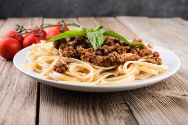 İtalyan spagetti bolognese sosu, et, peynir ve taze domates ve fesleğen - rustik ahşap zemin üzerine ev yapımı sağlıklı İtalyan Makarna. 