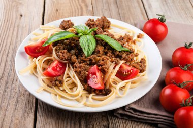 İtalyan spagetti bolognese sosu, et, peynir ve taze domates ve fesleğen - rustik ahşap zemin üzerine ev yapımı sağlıklı İtalyan Makarna. 