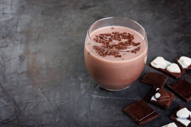 Karanlık bir tablo üzerinde muz ve çikolata parçaları ile çikolata güler yüzlü (süt).