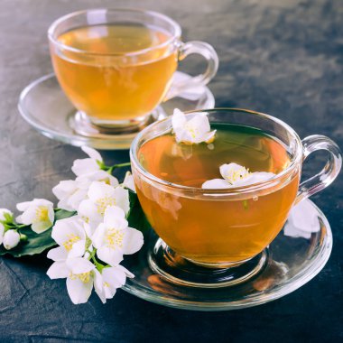 Karanlık bir beton zemin üzerine çay ve Yasemin çiçek bardak