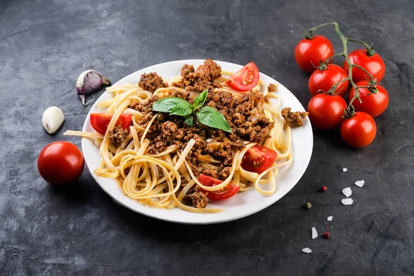Italian spaghetti   with bolognese sauce, meat, cheese and fresh tomatoes and  basil - homemade healthy italian pasta on dark  background.