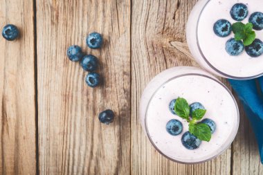 Güler yüzlü veya milkshake bir gözlük rustik ahşap masa, üstten görünüm üzerinde yaban mersini ile