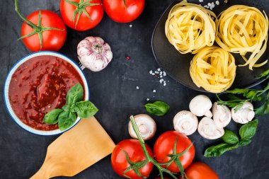 İtalyan makarna ve domates, koyu arka plan üzerinde yemek pişirmek için malzemeler. Üstten görünüm