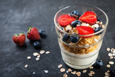 Sağlıklı Kahvaltı, taze meyveler ve karanlık bir arka plan üzerine müsli ile Doğal yoğurt
