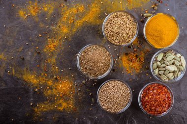 Yemek pişirmek için malzemeler. Koyu arka plan üzerinde bardaklarda farklı baharatlar. Üstten görünüm