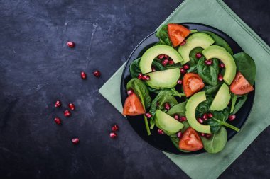 Avokado, domates, nar ile sağlıklı salata ve siyah bir arka plan, en iyi bebek ıspanak görüntülemek