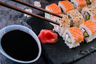 Philadelphia rulo ile somon, avokado, taş kadar yakın siyah arka plan üzerinde yılan balığı.