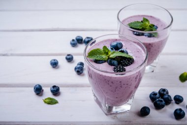 sağlıklı güler yüzlü veya beyaz ahşap zemin üzerinde taze yaban mersini ile sallamak