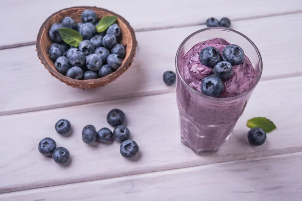 healthy smoothie or shake with fresh blueberries on a white wooden  background