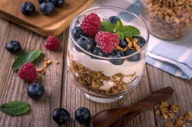 ahşap arka plan üzerinde bir bardak yoğurt ve taze yaban mersini ile granola 