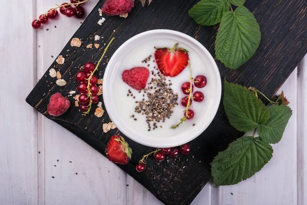 Healthy greek yogurt in a ceramic bowl with fresh berries and chia seeds, top view, selective focus