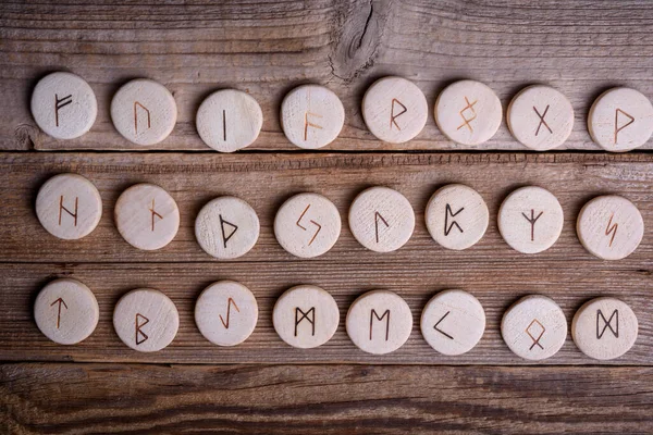 Wooden runes on a wood background. Ancient alphabet known as the futhark are divided into the three aetts