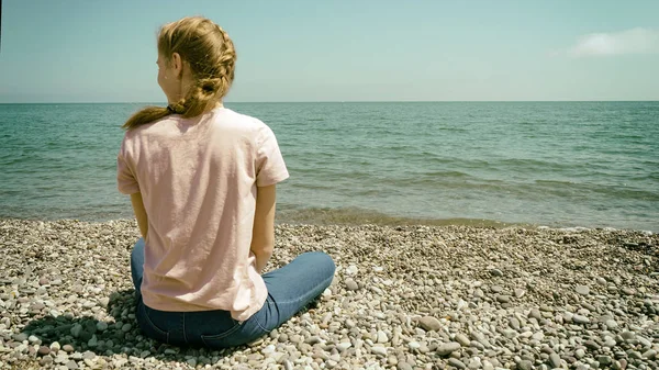La seule fois que vous devriez regarder en arrière est de voir jusqu'où vous venez motivation citation d'inspiration avec jeune adolescente contemplant la mer assis sur le littoral de galets. Image filtrée . — Photo