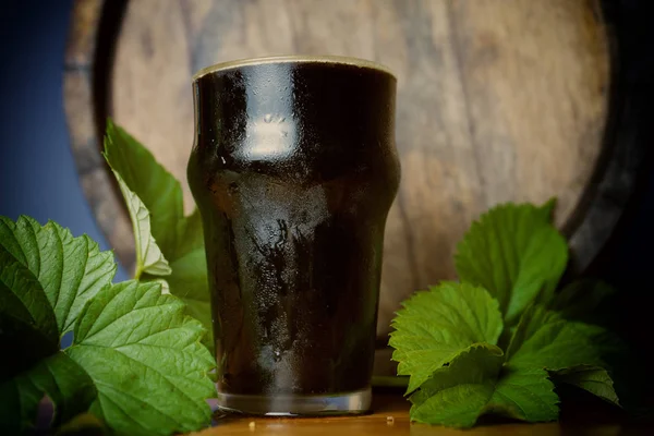 Pinte de bière brune bien avec une feuille de houblon sur le fond du baril. Gros plan . — Photo