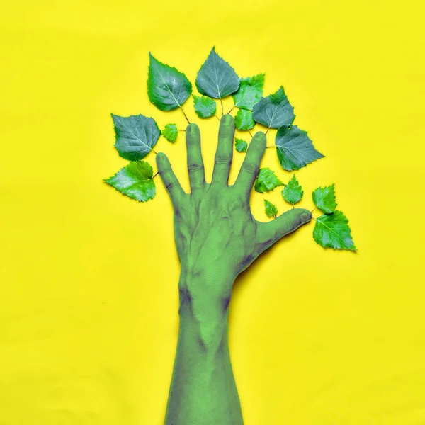 Concepto medioambiental. Mano con hojas en forma de árbol sobre fondo amarillo . — Foto de Stock