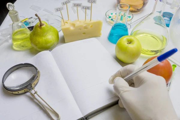 The food safety inspector is testing fruit from the market. Notebook with research report and blue pen on the lab table with the effect of selective focus