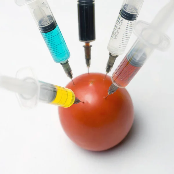 Modifikované rajče se stříkačkou na bílém pozadí — Stock fotografie