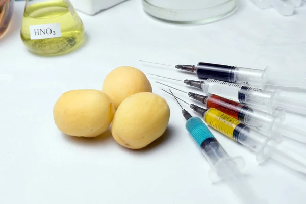 Enfoque selectivo de fruta con equipo médico y jeringas de colores con pesticidas sobre fondo blanco . — Foto de Stock