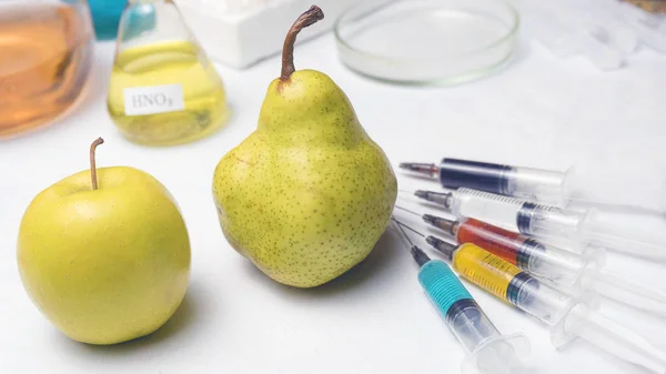 Seringas coloridas com fertilizantes químicos de diferentes cores em pêra e maçã. OGM e pesticidas . — Fotografia de Stock