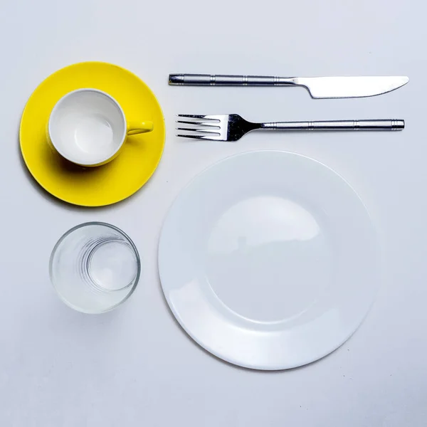 Coltello forchetta tazza di caffè e vetro su un tavolo bianco . — Foto Stock