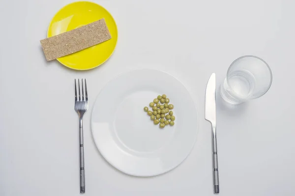 Concetto di dieta. pisello su un piatto bianco vuoto con coltello e forchetta — Foto Stock