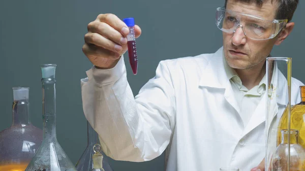 Health and medical, lab exam concept, close up of male doctor or technician holding test tube examining human centrifuged blood sample, red blood and serum making research in clinical laboratory