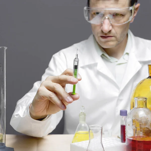 Дослідник тримає шприц з хімічним матеріалом у дослідницькій лабораторії — стокове фото