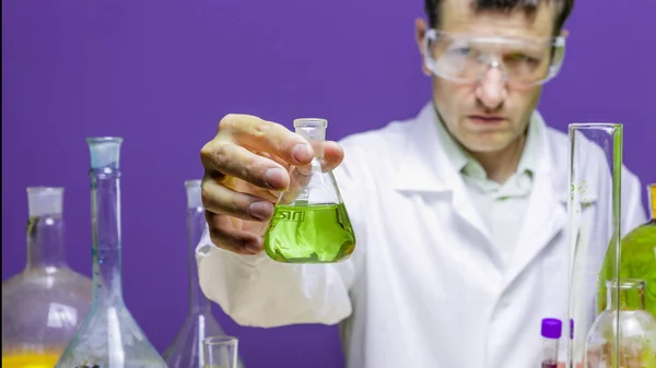 Um pesquisador médico ou científico masculino ou médico homem olhando para copo de solução de cor e pensar sobre química formular que pode ajudar as pessoas em um laboratório . — Fotografia de Stock