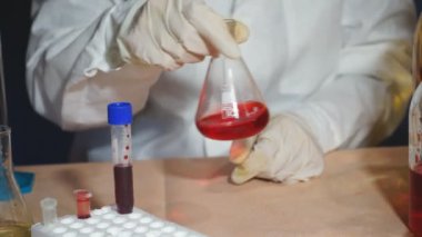 Kimya laboratuvarında kimyasal reaksiyon üzerinde çalışan bir bilim adamı. Cam şişede kimyasal reaksiyon. Laboratuvar çalışanı laboratuarda kimyasal deney yapıyor.