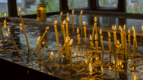 Lit candles candle light a small lamp kept permanently burning placed on sand in a church. — Stock Photo, Image