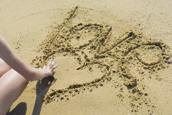 Mädchen am Strand zeichnet Herzen auf Sand — Stockfoto