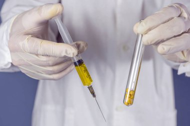 Araştırmacı soya fasulyesi ve şırınga ile bir test tüpü tutar. GDO konsepti. Seçici odaklama