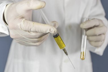 Araştırmacı soya fasulyesi ve şırınga ile bir test tüpü tutar. GDO konsepti. Seçici odaklama