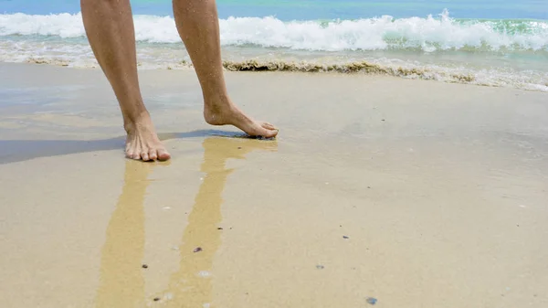 Closeup of womans feet walking on the beach during a golden sunset.