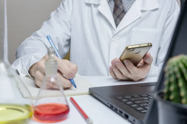 Férfi orvos vagy orvostanhallgató mobiltelefonnal dolgozik a laborban, közelkép. — Stock Fotó