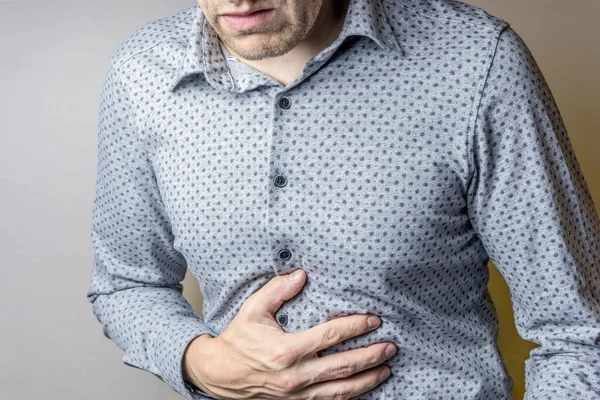 Gri arka planda karın ağrısı olan bir kişi..