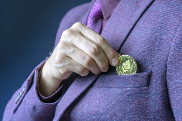 Empresario colocando un ETH etéreo en el bolsillo de su chaqueta en una vista cercana de sus dedos y la moneda . —  Fotos de Stock